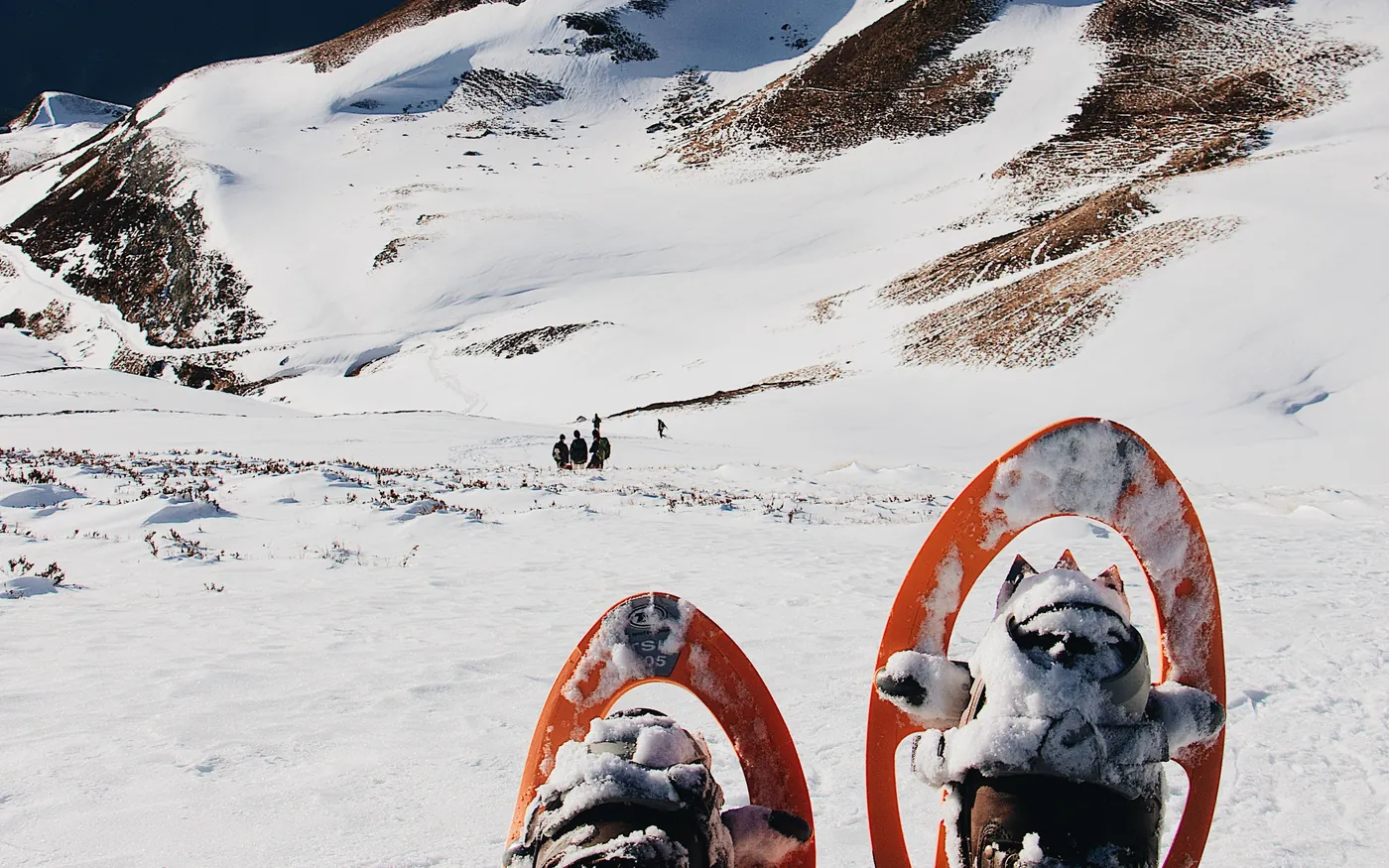 Snowshoer resting on a summit with a view over snow-covered mountains